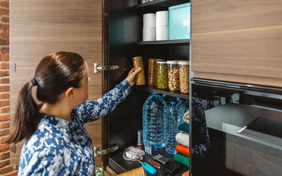 Side view of young woman looking through window