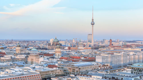 Fernsehturm amidst cityscape against sky during sunset