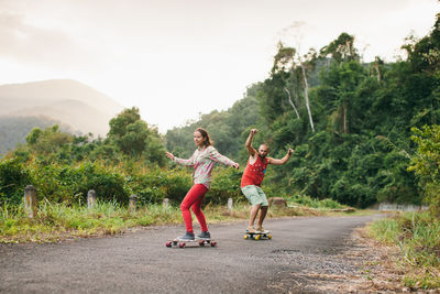 Friends skateboarding on road against sky