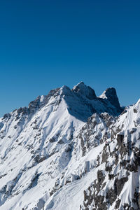 Scenic view of snowcapped mountains against clear blue sky