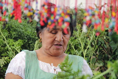 Mature woman wearing apron standing by plants