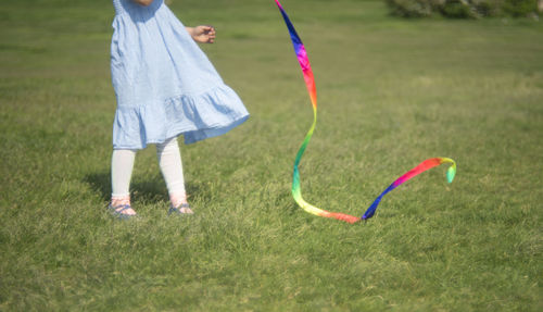 Low section of girl playing with ribbon on field