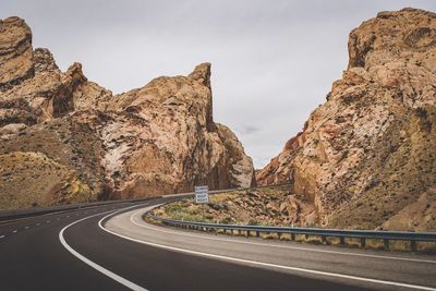 Road amidst rocky mountains against sky