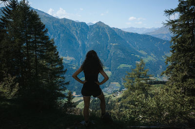 Rear view of woman standing in forest against mountain