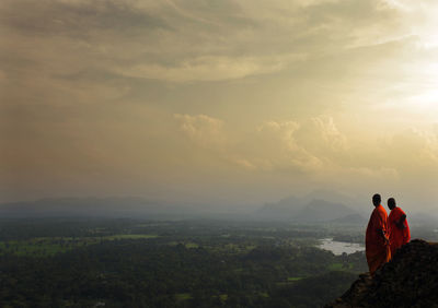 Monk standing on mountain against sky