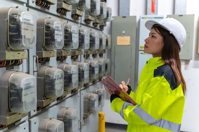 Side view of engineer inspecting electrical outlets at factory