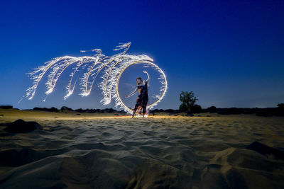 Full length of woman spinning wire wool at dusk