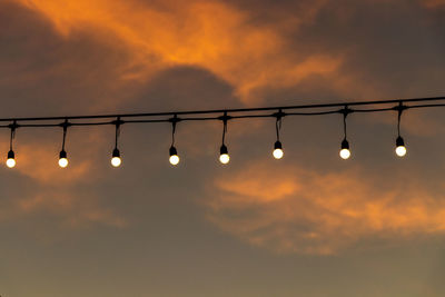 Low angle view of illuminated lights against sky during sunset