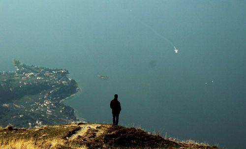 Rear view of man standing on mountain against sea