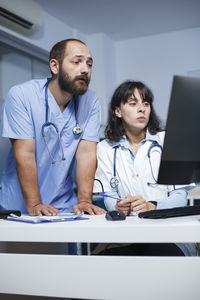 Female doctor and colleague working at desk in office