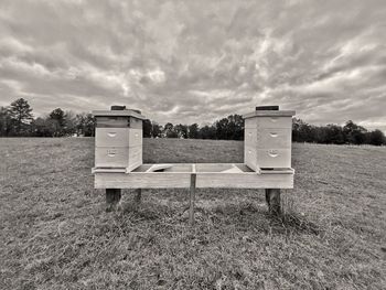 Empty bench on field against sky