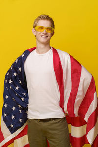 Portrait of young woman standing against yellow background