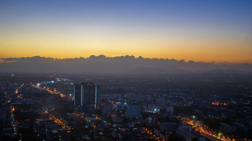 High angle view of illuminated city against sky at sunset