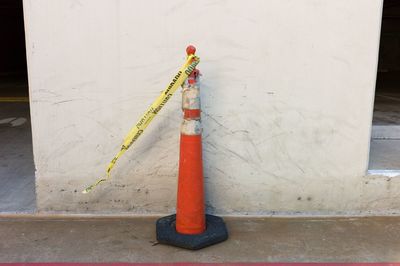Old traffic cone by white wall