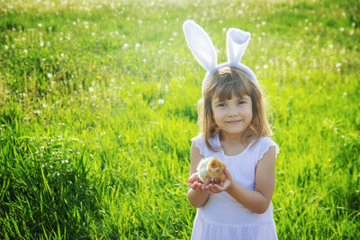 Portrait of young woman with teddy bear on grassy field