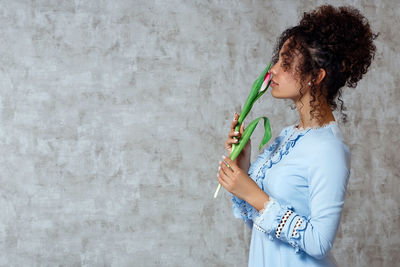 Side view of woman standing against wall