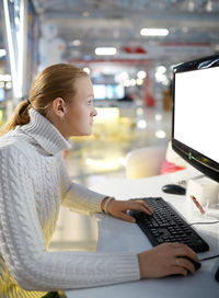 Side view of woman using computer at office