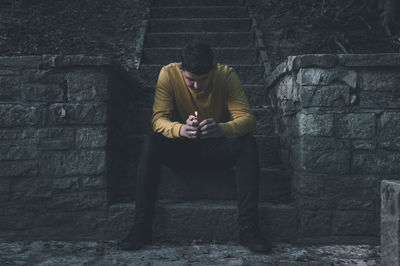 Young man sitting on wall