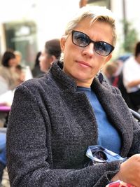 Portrait of mature woman wearing sunglasses while sitting at sidewalk cafe