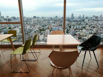 Empty chairs and table in restaurant against buildings in city