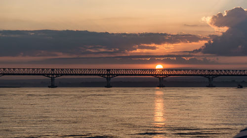 Bridge over sea against sky during sunset