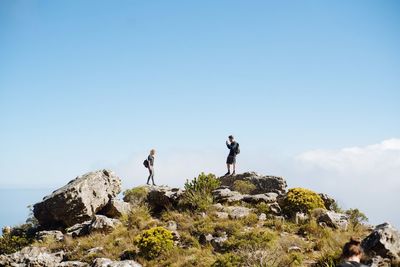 Men standing on rock against sky