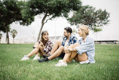 Happy friends sitting on grassy field