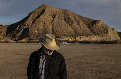 Adult man in cowboy hat standing against mountains in tabernas desert. almeria, spain