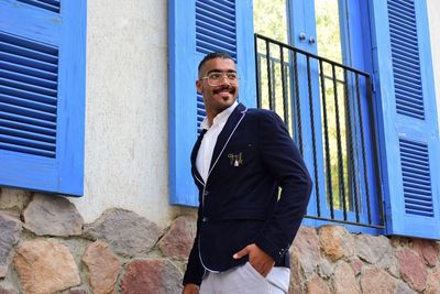Portrait of young man standing against wall
