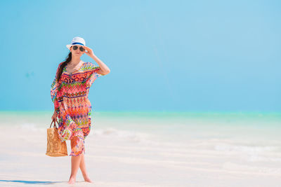 Full length of woman standing on beach against sky