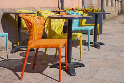 Empty chairs and tables at sidewalk cafe