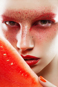 Close-up portrait of serious young woman with watermelon slice