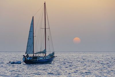 Sailboat sailing on sea against sky during sunset