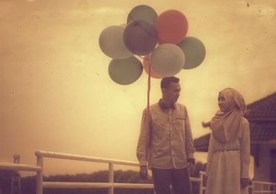 Woman looking at boyfriend holding balloons