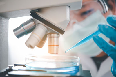 Close-up of doctor examining over microscope