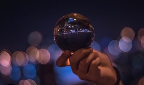 Close-up of hand holding illuminated lighting equipment at night