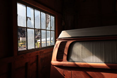 Morning light through broken window on side of volkswagen bus in barn