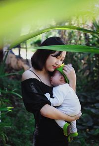 Mother carrying daughter while standing in park