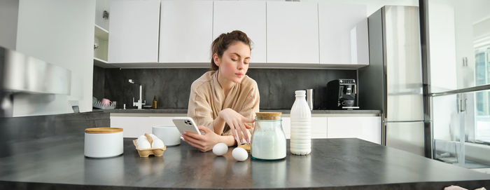 Portrait of young woman sitting on table at home