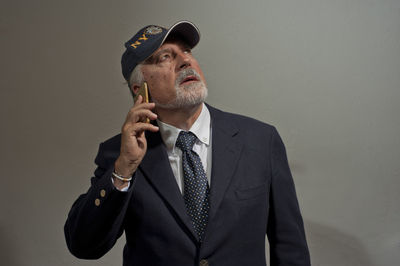 Portrait of man wearing hat standing against gray background