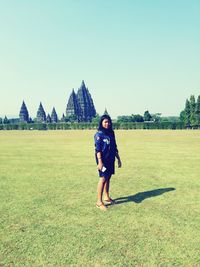 Full length of woman standing on field against clear sky