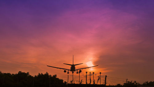 Low angle view of silhouette airplane against sky during sunset