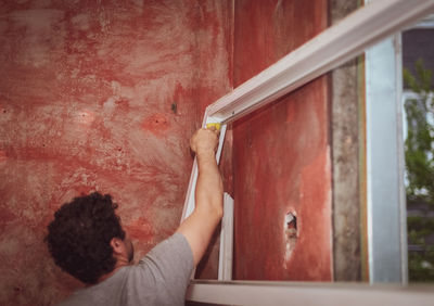 Caucasian male builder washes window frames with a sponge.