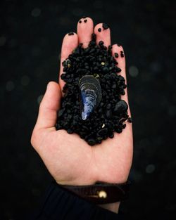 Close-up of man holding leaf against black background