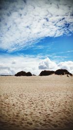 Scenic view of desert against cloudy sky