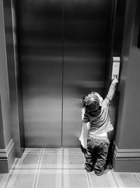 Rear view full length of boy pressing elevator button