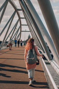 Rear view of people walking on bridge