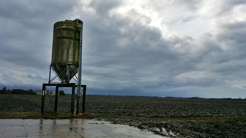 Water tower on field against sky