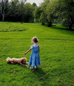 Full length of girl with dog on grassy field