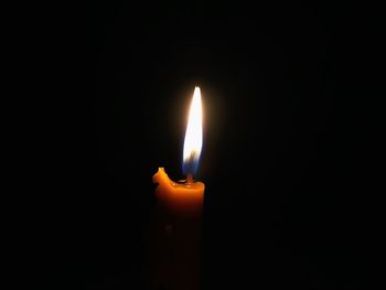 Close-up of lit candle against black background